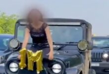 women sits on SUV bonnet